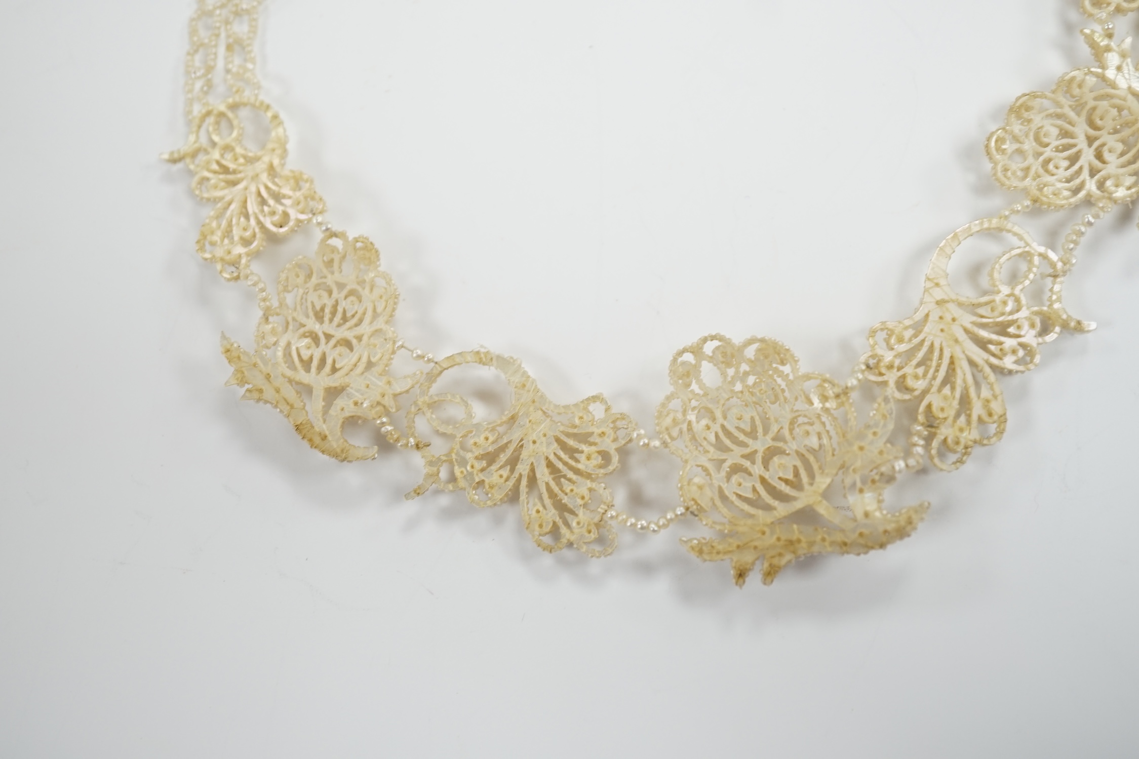 A cased Regency twin strand seed pearl choker necklace with scrolling floral motifs and yellow metal clasp, 34cm.